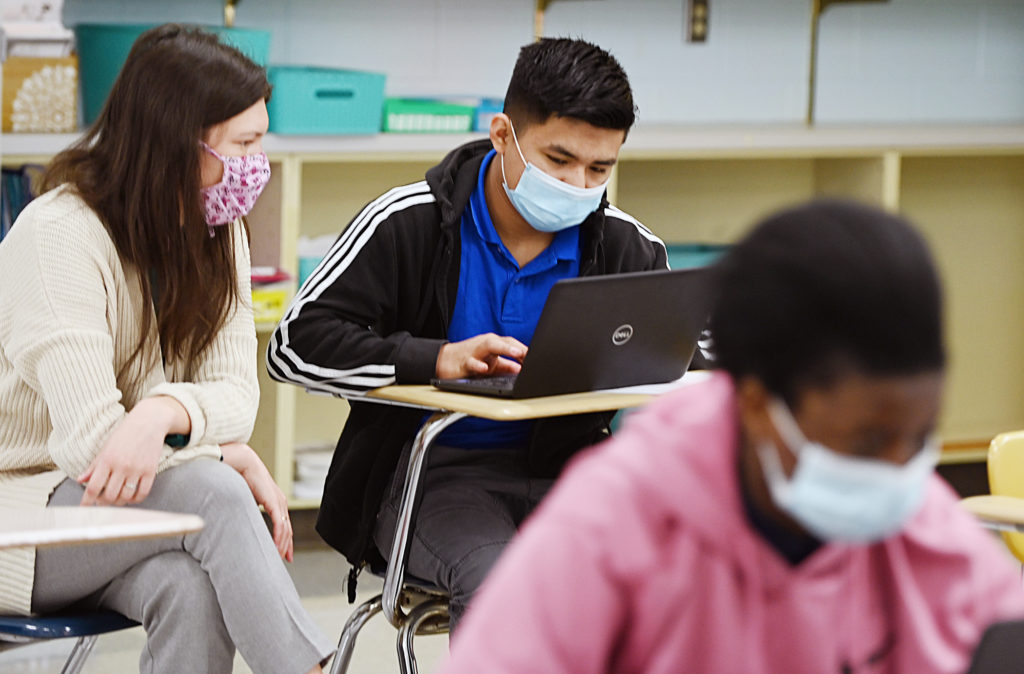 teacher assisting a student with classwork